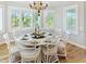 Elegant dining room with a round table, white chairs, and large windows at 520 Kumquat Dr, Anna Maria, FL 34216