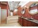 A luxurious bathroom with dual sinks, a soaking tub, and red wallpaper at 9750 53Rd E Dr, Bradenton, FL 34211