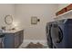 Modern laundry room with gray cabinets, washer, dryer, and floating shelves at 18212 Cayo Largo Pl, Bradenton, FL 34202