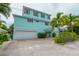 Three-story light blue home with three-car garage at 796 Jacaranda Rd, Anna Maria, FL 34216