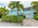 Two-story light teal home with white garage doors at 796 Jacaranda Rd, Anna Maria, FL 34216
