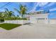 Modern beachfront home with a white exterior, two-car garage, and a grassy yard at 308 S Bay Blvd, Anna Maria, FL 34216