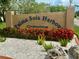 Palma Sola Harbour Condominium sign surrounded by white rocks and vibrant red flowers at 4104 Catalina Dr, Bradenton, FL 34210