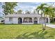 Ranch-style home with covered porch, mature landscaping, and a two-car garage at 13479 Newport Ave, Port Charlotte, FL 33981