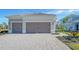 Two-car garage, light gray exterior, paved driveway, landscaping at 10142 Crystal Isles Cir, Sarasota, FL 34241