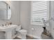 Elegant powder room with pedestal sink, toilet, and a decorative mirror at 7940 Redonda Loop, Bradenton, FL 34202