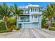 Two-story light blue house with white accents; palm trees and landscaping in front at 106 7Th S St, Bradenton Beach, FL 34217