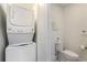 White washer and dryer combo in a small laundry room with toilet and additional storage at 1703 N Tamiami Trl # 210, Sarasota, FL 34234