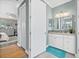 A bathroom and walk-in closet leading to the bedroom with wood-look floors and a vanity with double sinks at 17335 Polo Trl, Bradenton, FL 34211