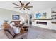 Inviting living room with a cozy fireplace, ceiling fan, comfortable furniture, and access to an adjacent seating area at 17335 Polo Trl, Bradenton, FL 34211