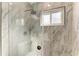 A walk-in marble shower with a rainfall shower head and a framed window, providing natural light at 2435 Sumatran Way # 35, Clearwater, FL 33763