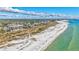 Beautiful aerial view of a beachfront condo complex next to white sands and blue ocean, with city views in the distance at 420 Beach Rd # 203, Sarasota, FL 34242