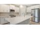 Bright kitchen with white cabinets, stainless steel appliances, and a herringbone backsplash at 26903 Pavin Dr, Englewood, FL 34223