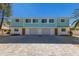 Newly constructed three-unit building, featuring light teal exterior and attached garages at 303 65Th St # B, Holmes Beach, FL 34217