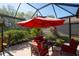 Relaxing patio with covered seating area, red umbrella, and lush landscaping at 415 Fairway Isles Ln, Bradenton, FL 34212