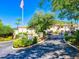 Community entrance with lush landscaping, flagpole, and signage at 4495 Longmeadow # 77, Sarasota, FL 34235