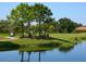 Golfers on the green near a pond, golf cart path, and trees at 4495 Longmeadow # 77, Sarasota, FL 34235