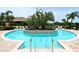 Community pool featuring a unique island with palm trees and luxurious lounge chairs around the perimeter at 5397 Bartolomeo St, Sarasota, FL 34238