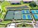 Aerial view showcasing multiple well-maintained tennis courts surrounded by lush landscaping at 5397 Bartolomeo St, Sarasota, FL 34238