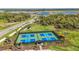 Aerial view of green and blue pickleball courts surrounded by trees, houses, and a scenic view of the neighborhood at 10124 Silent Night Ln, Sarasota, FL 34241