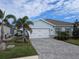 Two-car garage, light blue exterior, paver driveway, landscaping at 16351 Coconut Palm Dr, Port Charlotte, FL 33953