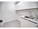 Bright laundry room with white cabinets and modern sink at 230 W Pine Valley Ln, Rotonda West, FL 33947