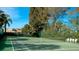Community tennis court with surrounding trees and a view of a Publix at 3705 E Bay Dr # 212, Holmes Beach, FL 34217