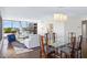Spacious living room featuring a glass dining table, white sofas, and large windows with treetop views at 545 Sanctuary Dr # B406, Longboat Key, FL 34228