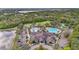 An aerial view shows a community center with swimming pools, a clubhouse, and lush landscaping near a lake at 7042 Twin Hills Ter, Lakewood Ranch, FL 34202