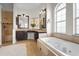 Elegant bathroom with a soaking tub, dark wood vanity, granite countertop, and arched window at 7042 Twin Hills Ter, Lakewood Ranch, FL 34202