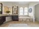 Bright bathroom featuring a soaking tub, granite countertop, modern fixtures, and arched windows at 7042 Twin Hills Ter, Lakewood Ranch, FL 34202