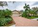 Brick driveway leads to a charming house with lush landscaping at 7117 Victoria Circle, University Park, FL 34201