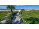 Beach access walkway with lush vegetation and seating at 1200 E Peppertree Ln # 607, Sarasota, FL 34242