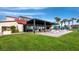 Covered outdoor dining area with white tables and chairs next to green lawn at 2045 Gulf Of Mexico Dr # M1-502, Longboat Key, FL 34228