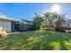 Large, grassy backyard with a screened pool enclosure and tropical plants at 348 Red Ash Cir, Englewood, FL 34223