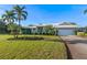 Charming one-story home with a white tiled roof, landscaped yard, and palm trees at 348 Red Ash Cir, Englewood, FL 34223