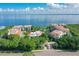 Aerial view of condo buildings with red tile roofs surrounded by lush trees and overlooking the sea at 350 Gulf Of Mexico Dr # 211, Longboat Key, FL 34228
