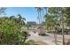 Gated community entrance with lush landscaping, palm trees, and a pond at 350 Gulf Of Mexico Dr # 211, Longboat Key, FL 34228