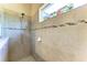 Modern bathroom with tiled walk-in shower and decorative stained-glass window at 1387 Still River Dr, Venice, FL 34293