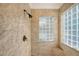 Beautiful bathroom featuring marble-tiled walls, a shower with a modern fixture, and glass block windows at 1732 Hillview St, Sarasota, FL 34239