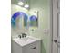 Bathroom with a unique circular mirror, white vanity, and soft green walls at 4151 Via Sienna Cir, Sarasota, FL 34243