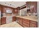 Modern kitchen with stainless steel appliances, granite counters, brown cabinets, and tile floor at 5561 Golf Pointe Dr, Sarasota, FL 34243