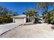 Cute bungalow with a light gray exterior, wood garage door, and tropical landscaping at 633 Calle De Peru, Sarasota, FL 34242