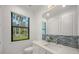 Modern bathroom with a glass shower, white cabinets, and blue tile at 7051 Turtle Ln, Sarasota, FL 34241