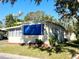 Side view of a tan mobile home with blue accents and landscaping at 103 Oakwood Blvd, Sarasota, FL 34237