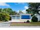 Charming single-story home featuring cream siding, a red brick foundation and a large blue awning for shade at 103 Oakwood Blvd, Sarasota, FL 34237