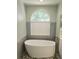Beautiful white freestanding tub with modern fixtures and a large arched window at 13634 7Th Avenue Ne Cir, Bradenton, FL 34212