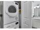 Laundry area features a stacked washer and dryer with a view to a clean and well-lit bathroom at 2124 N Tamiami Trl # 103, Sarasota, FL 34234