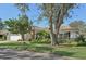 Landscaped one-story home with a brick facade and mature trees in the front yard at 5808 Garden Lakes Majestic, Bradenton, FL 34203