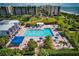 Community pool with blue umbrellas, lounge chairs, and adjacent buildings at 1085 Gulf Of Mexico Dr # 301, Longboat Key, FL 34228